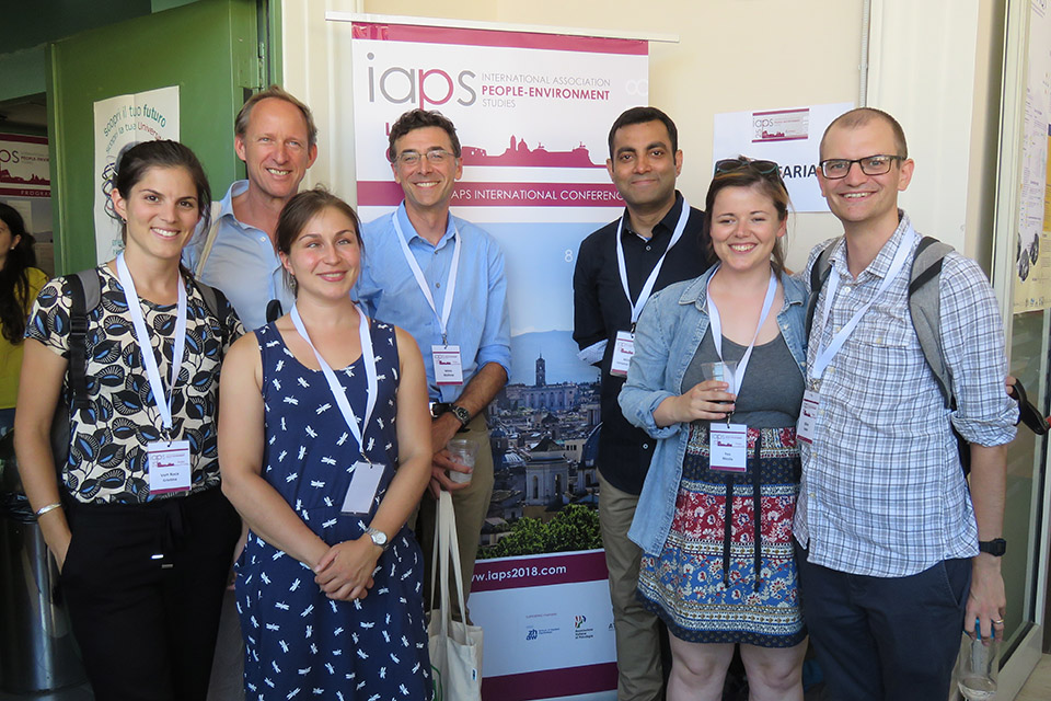 BlueHealth researchers smile in front of an IAPS banner