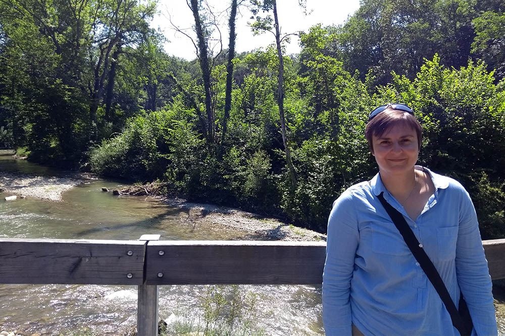 Sandrine standing on a bridge in front of a shallow rocky river