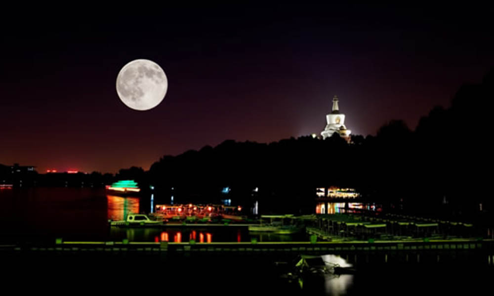 A full moon rises over the lake in Beihai park