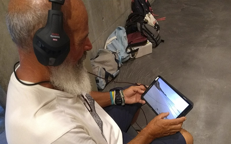 A man looks at a video of a blue space on a digital tablet